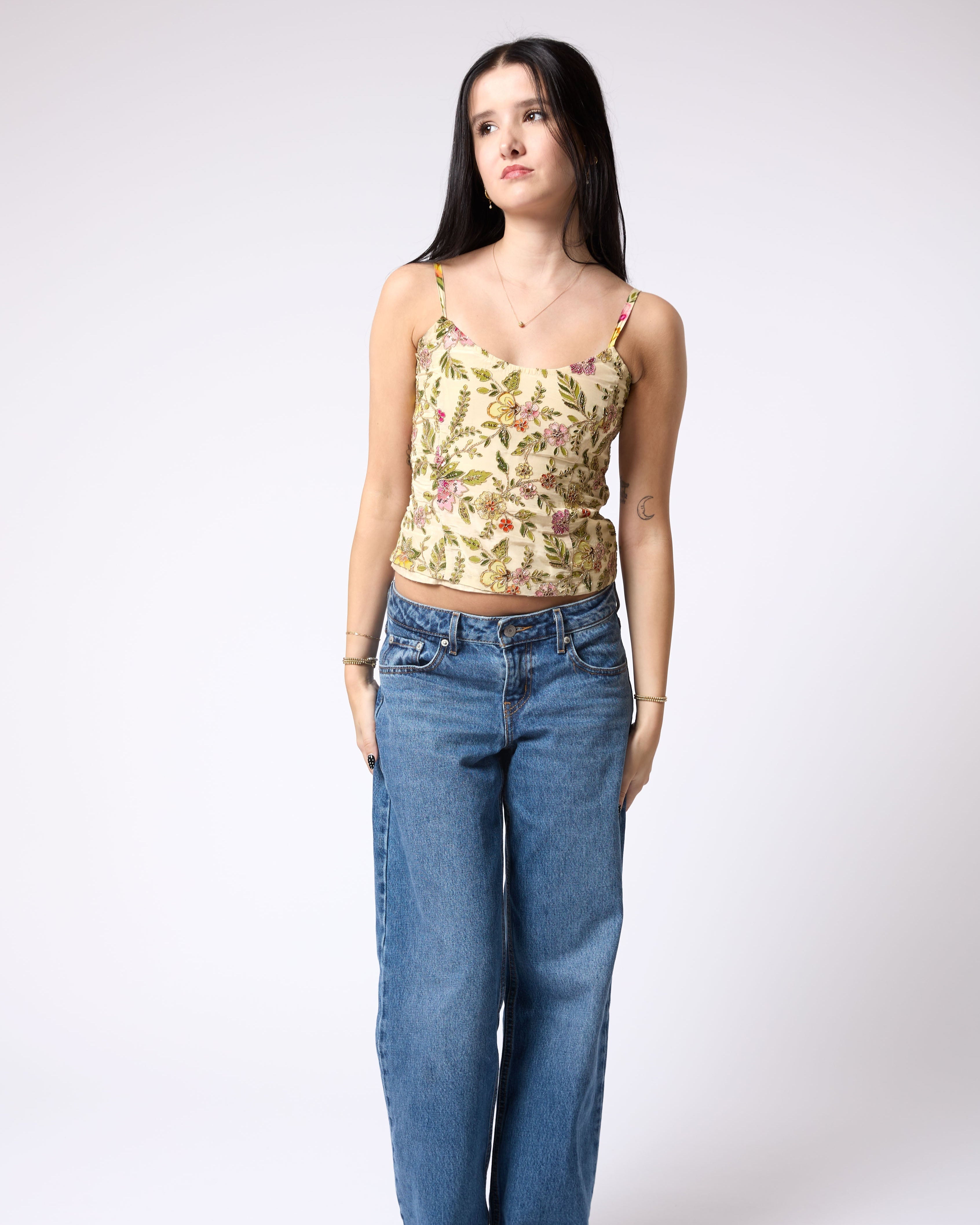 Woman wearing a floral top and blue jeans on a white background